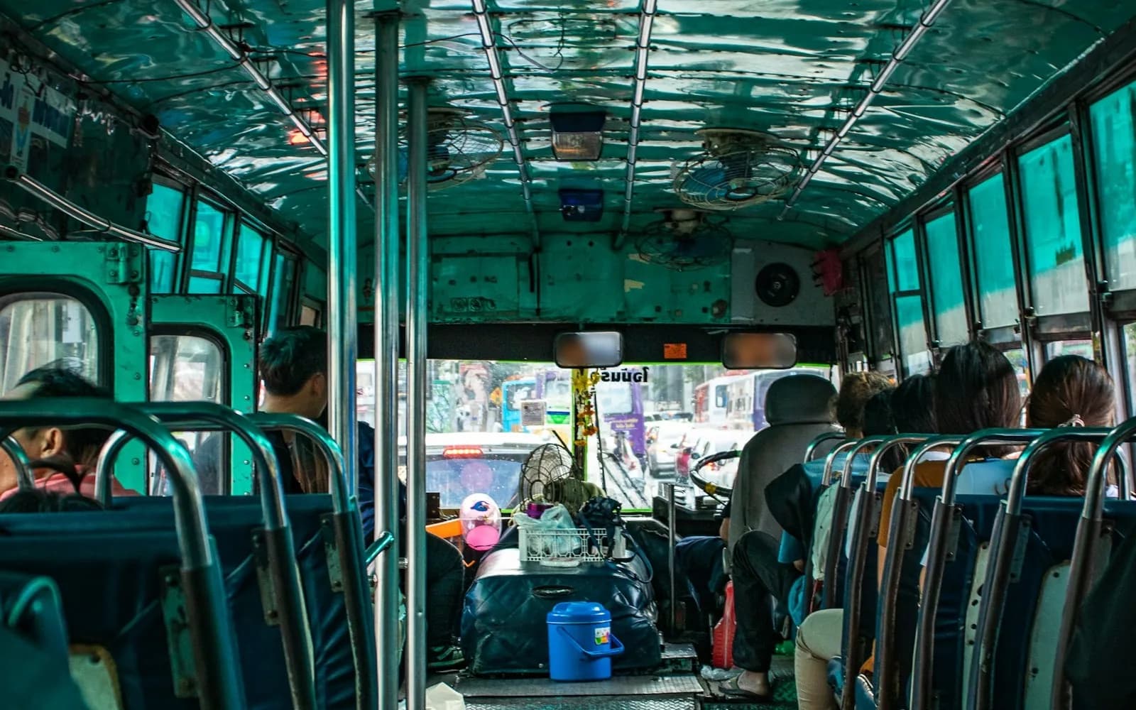Městský autobus v Bangkoku zevnitř: ventilátory u stropu, modrá sedadla a cestující